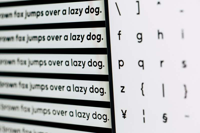 Person analyzing word frequency charts on dual monitors with linguistic data visualizations
